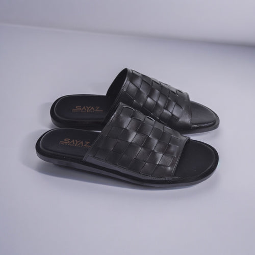 A pair of black leather slippers with a textured pattern, displayed against a white background.