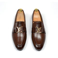 A pair of brown leather shoes with a distinctive LV (Louis Vuitton) buckle, displayed against a white background.