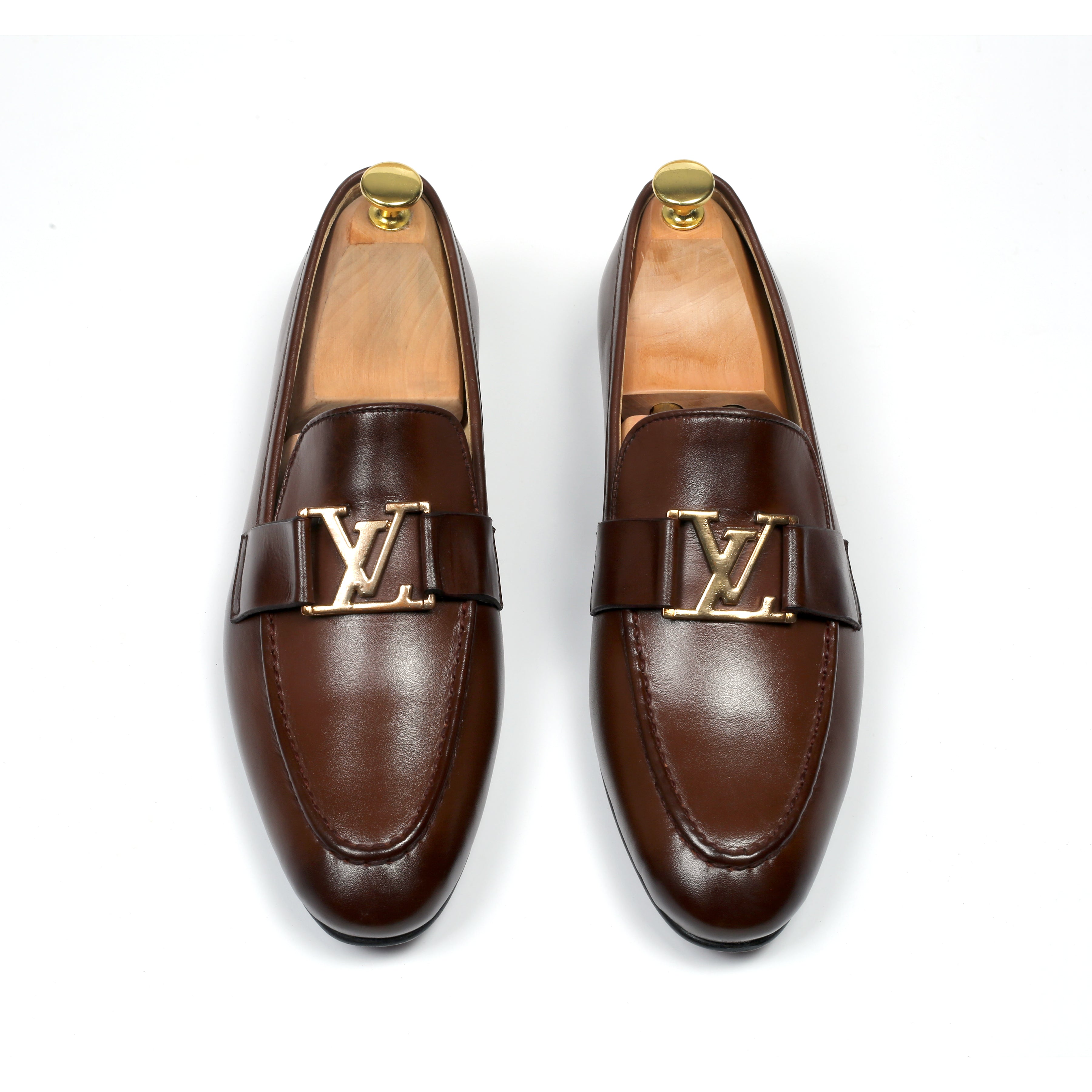 A pair of brown leather shoes with a distinctive LV (Louis Vuitton) buckle, displayed against a white background.