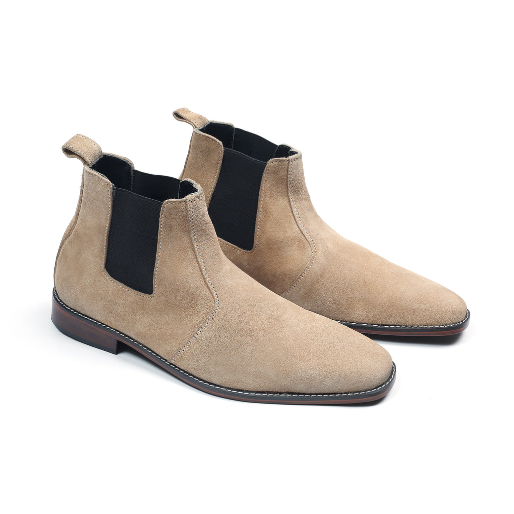Pair of beige suede Chelsea boots with black elastic on a white background